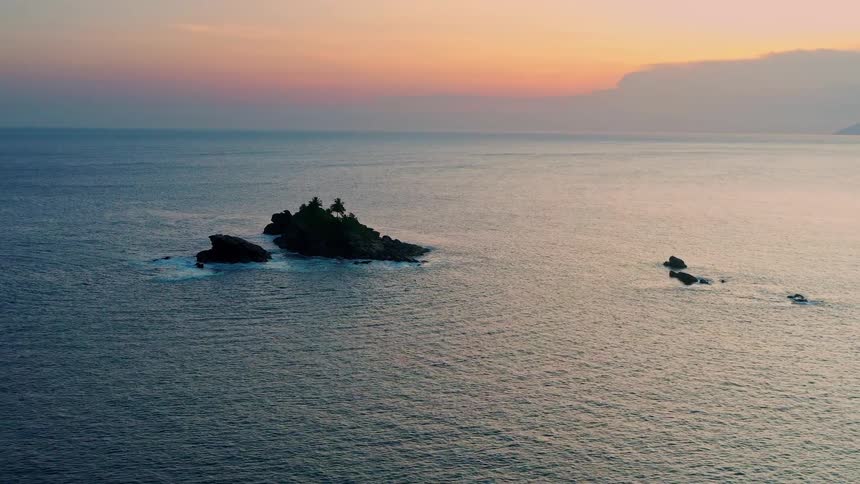A large rock formation protrudes slightly above the ocean water