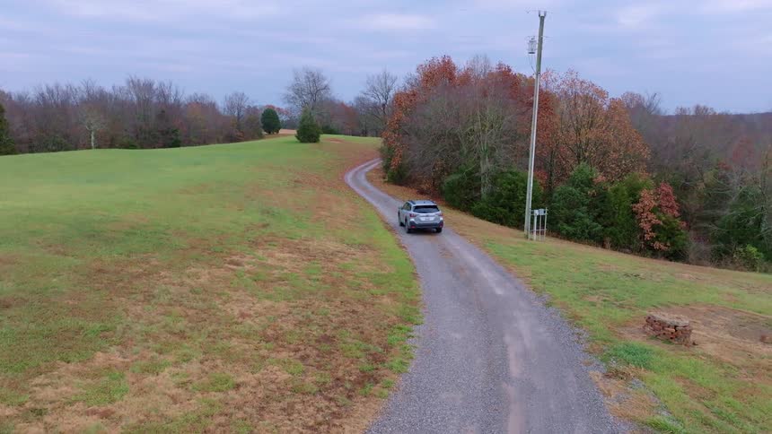 Car driving on a gravel road in a rural area with autumn trees