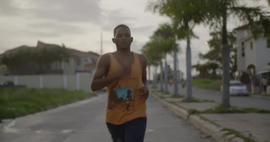A man is jogging down a suburban street during the day