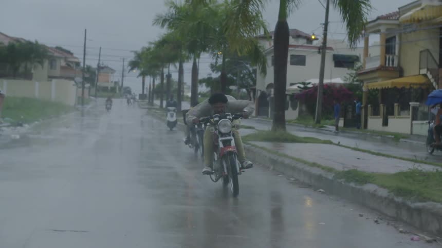 Two people are riding motorcycles in the rain