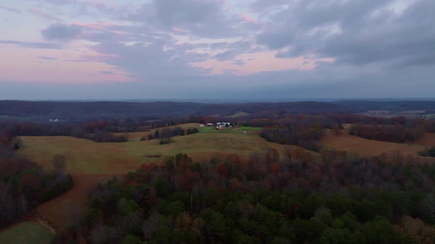 An aerial shot of countryside fields and trees at dusk