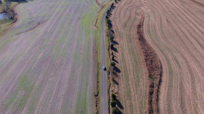 Narrow road cuts through farmland seen from above