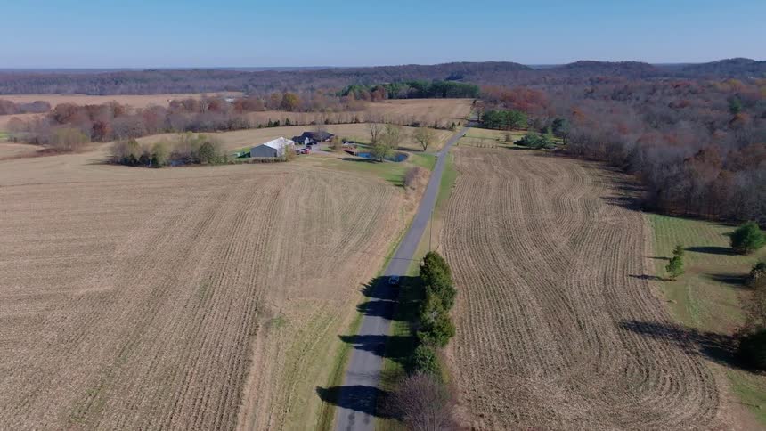 Rural road surrounded by farmland and a few buildings