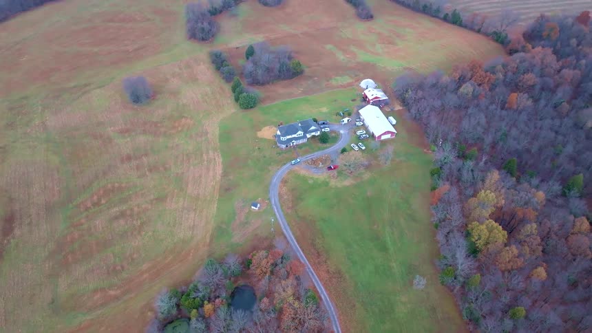 Aerial panorama of a farm in a grassy field with trees
