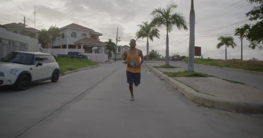 A man is jogging down a suburban street during the day