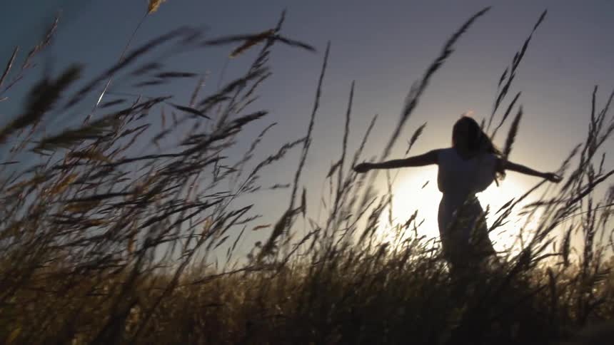 A woman twirls as the sun sets behind her