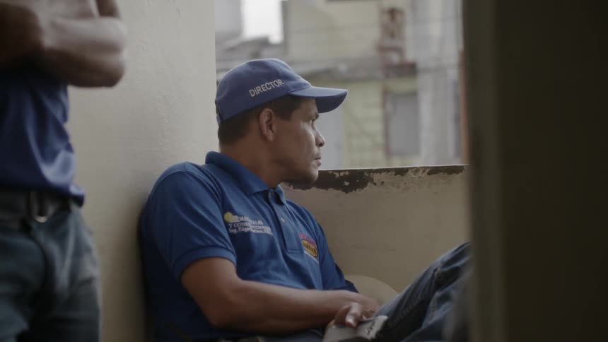 Man sitting and looking around in his workplace while wearing a cap