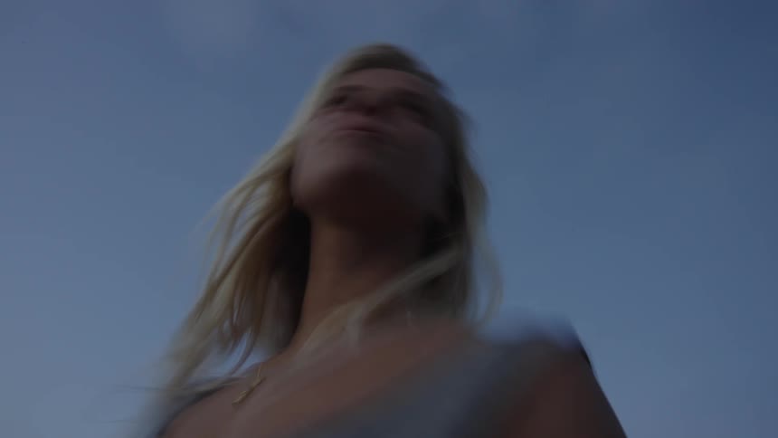 Blonde woman blurred in the foreground with a blue sky in the background