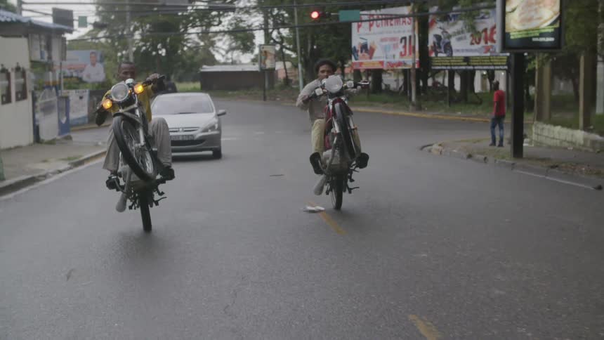 Two men pop wheelies on their motorcycles