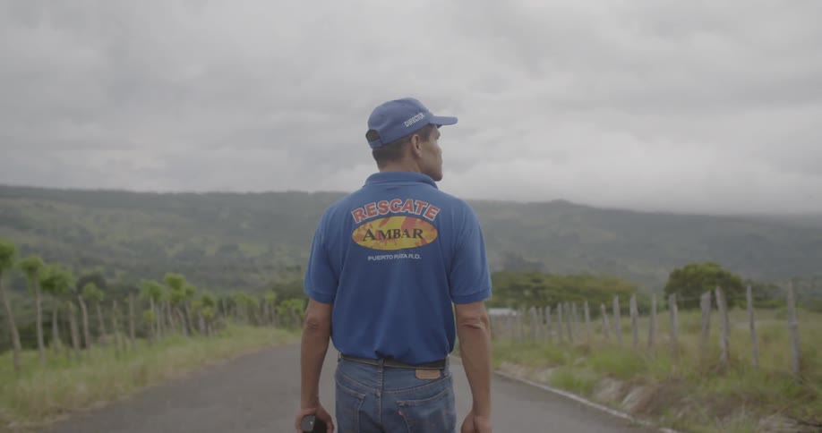 A man walks on a rural road on a cloudy day