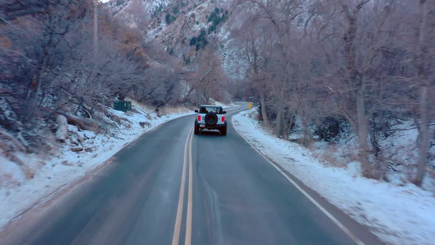 Car driving on a winding road through a snowy forest area