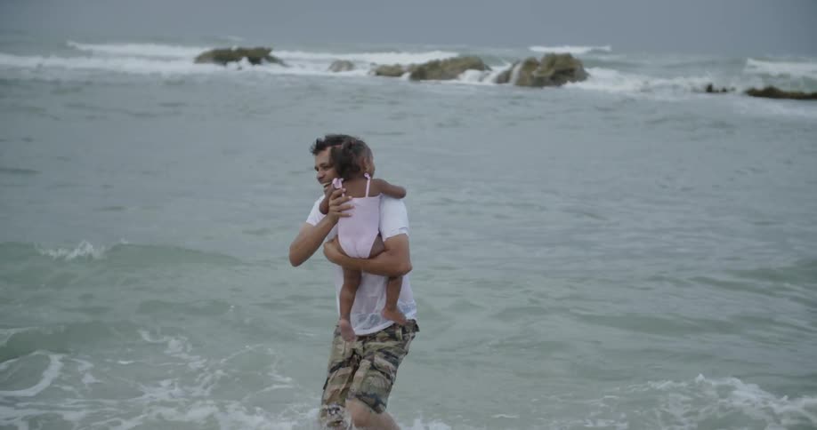 A man holds his daughter in the ocean