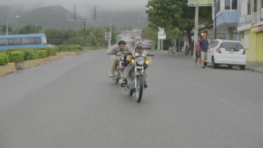 Two men riding motorcycles downtown street on foggy day