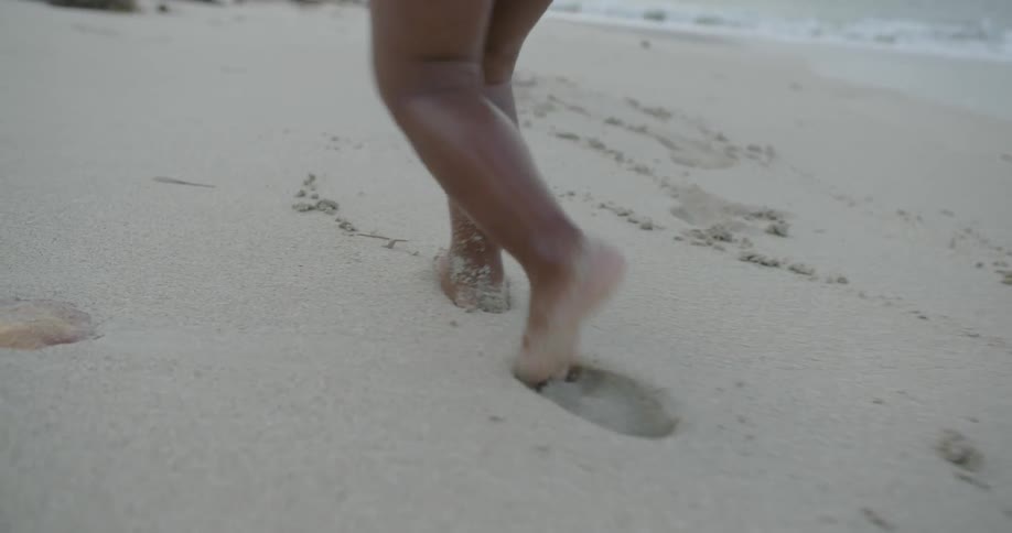 Man and toddler girl walking in sand on beach