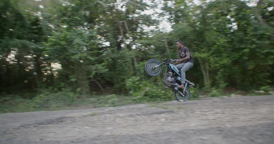 A man riding a motorcycle does a wheelie