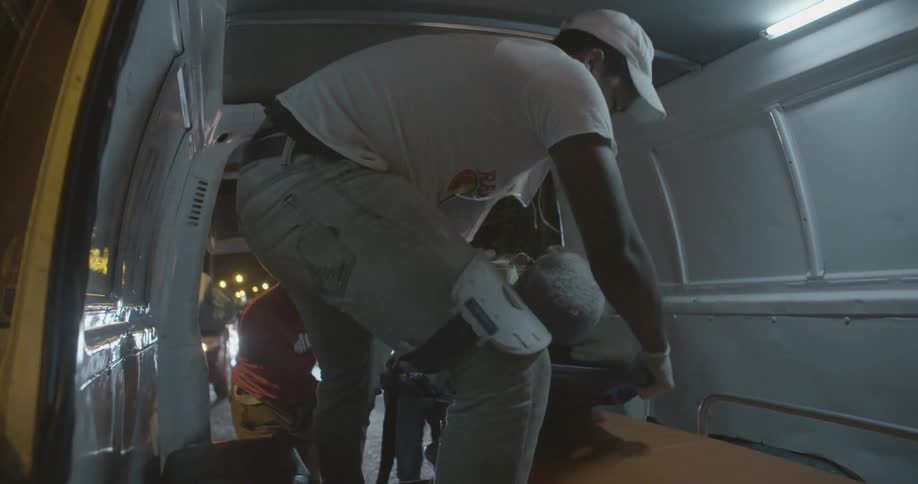Paramedics pull a man into an ambulance