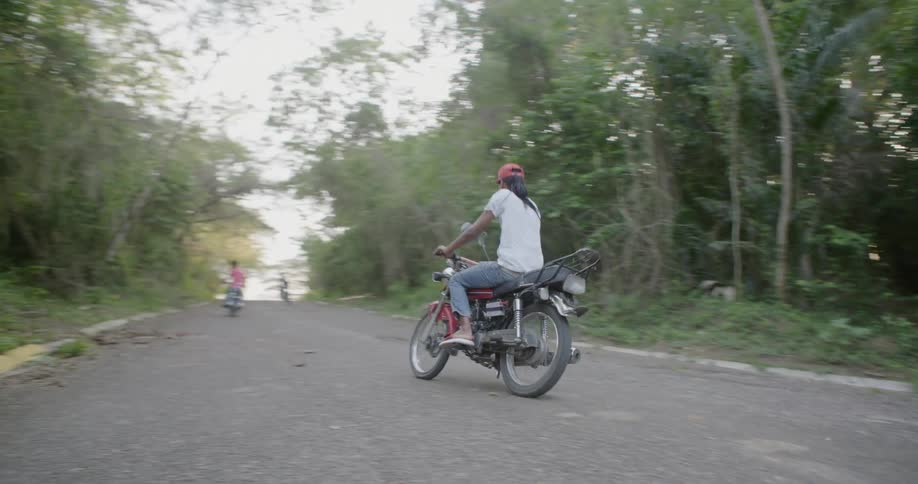 Bikers riding down a wooded street