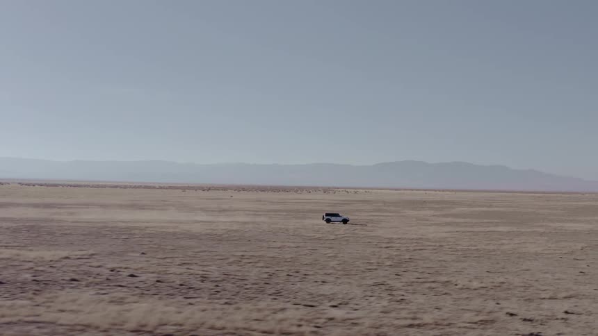 An suv drives through a desert on a sunny day