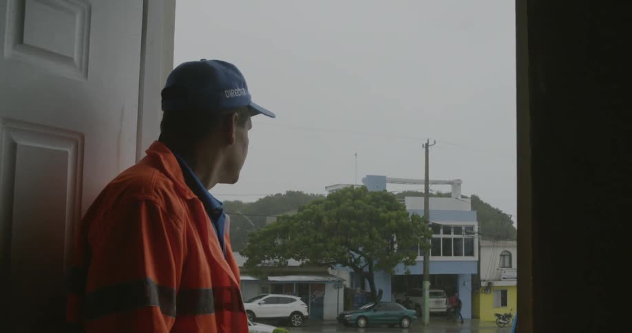 A man looks out a door towards buildings