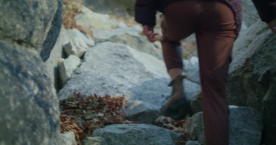 Female hiking up large boulders in the fall