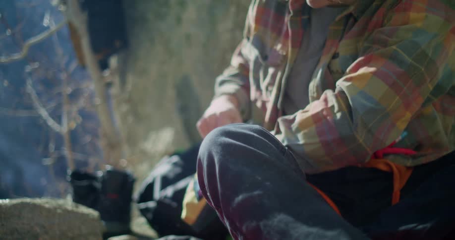 A mountain climber prepares to climb by rubbing chalk on his palms at midday