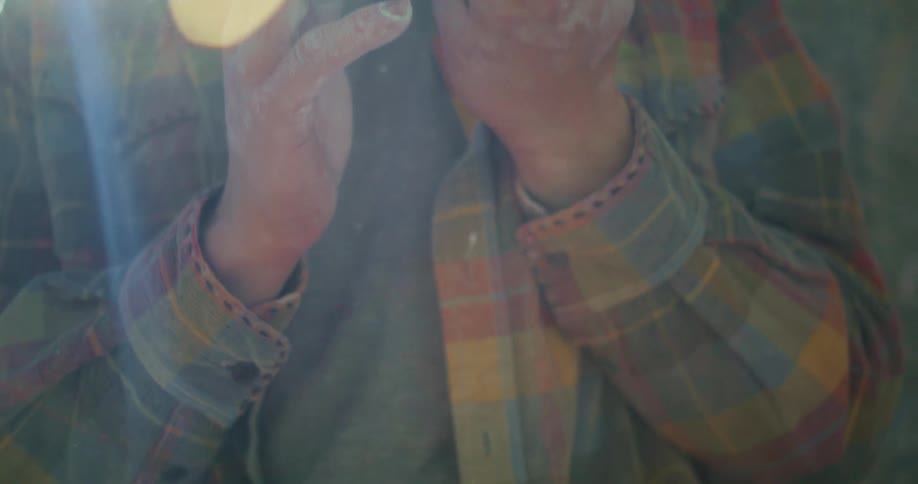 A mountain climber prepares to climb by rubbing chalk on his palms at midday