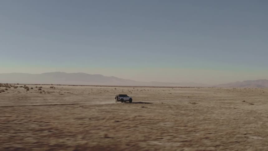 Motor vehicle creates a cloud of dust while driving across a plain on a foggy day