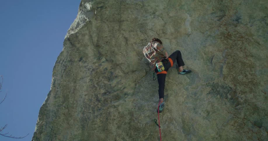 A mountain climber ascends a mountain at midday