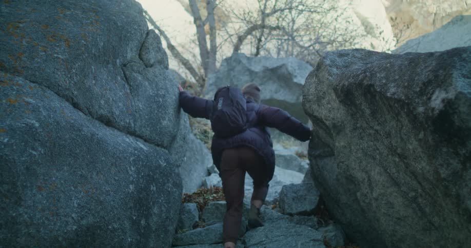 Female hiking in the canyon through large boulders