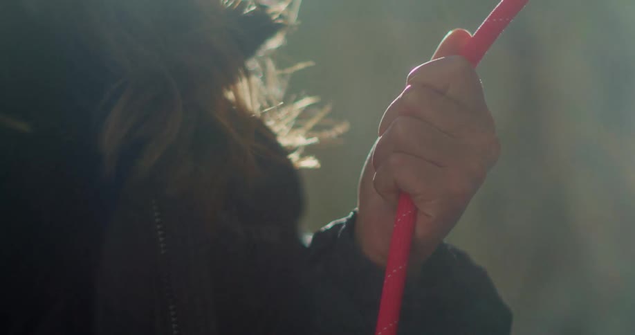 Closeup of a womans hand holding a rope on a mountain wall