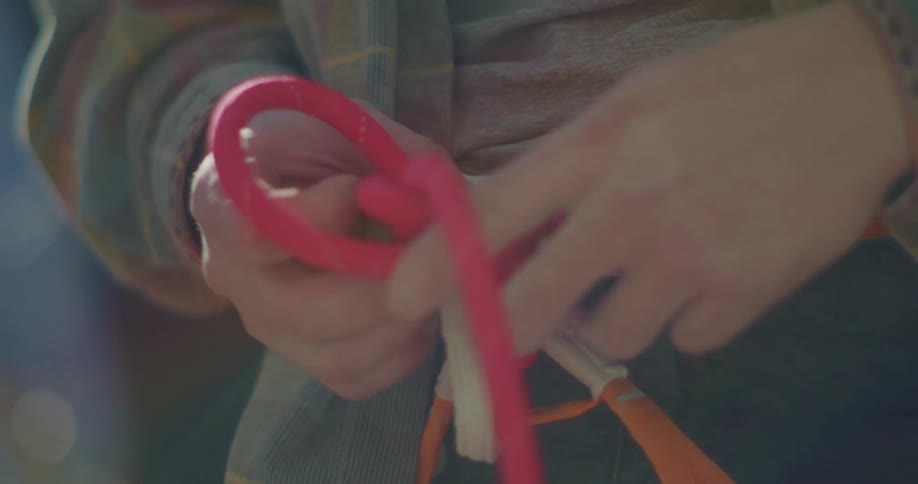 Person adjusts knot on a climbing rope attached to a harness