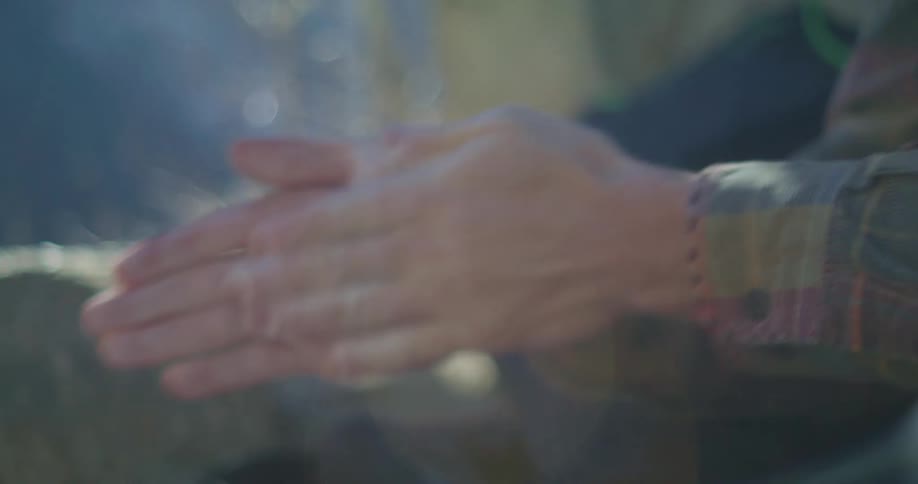 A man rubbing his hands together vigorously then reaching for a bag below