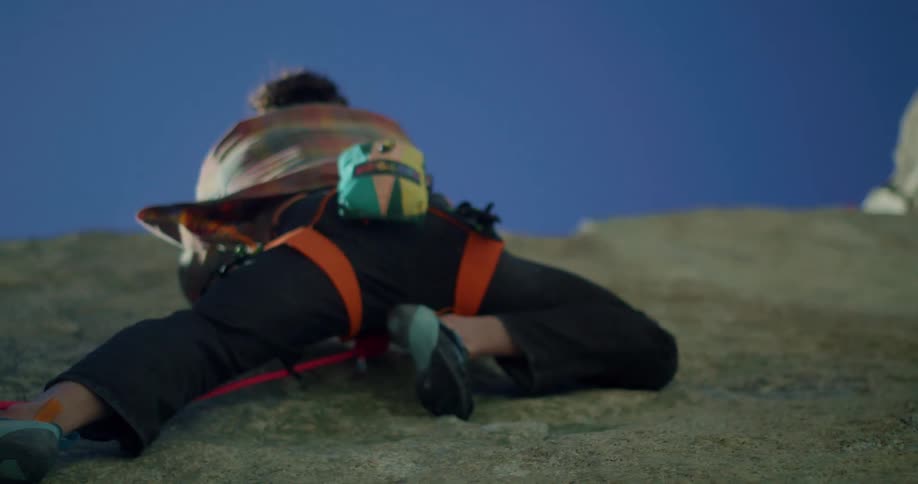 Person climbing a rock wall wearing safety gear and climbing shoes