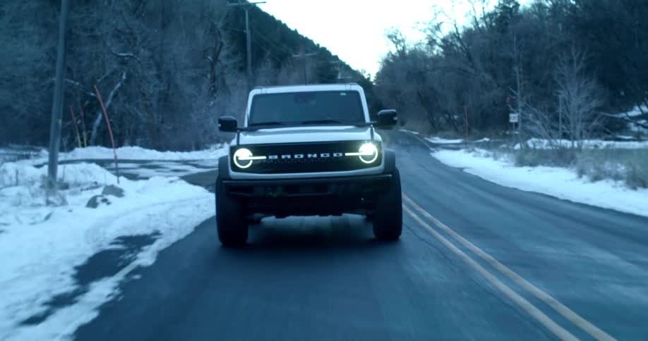 Ford bronco drives along a road with snow on the sides