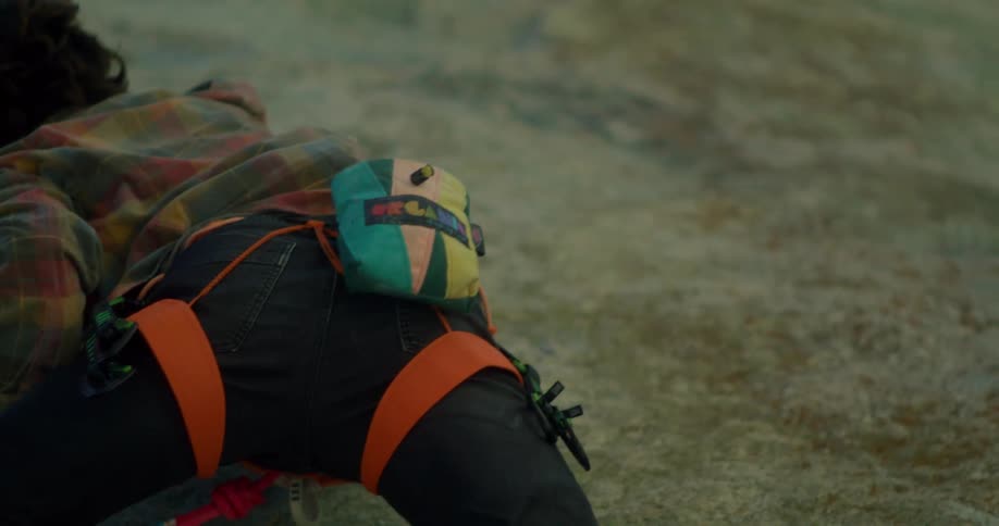 The man is slowly climbing up the cliff of the mountain