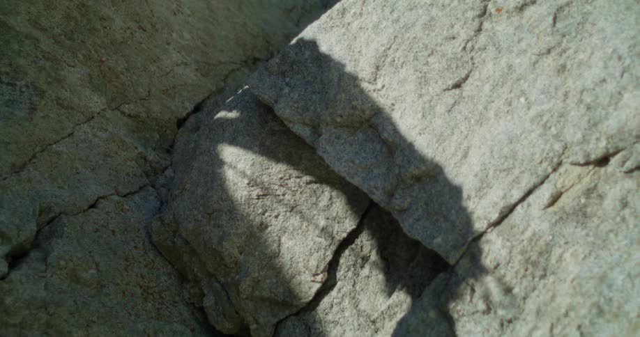 A shot shows a persons shadow cast onto a rock formation as they walk the shadow gradually moves up the rock face and eventually disappears from the frame