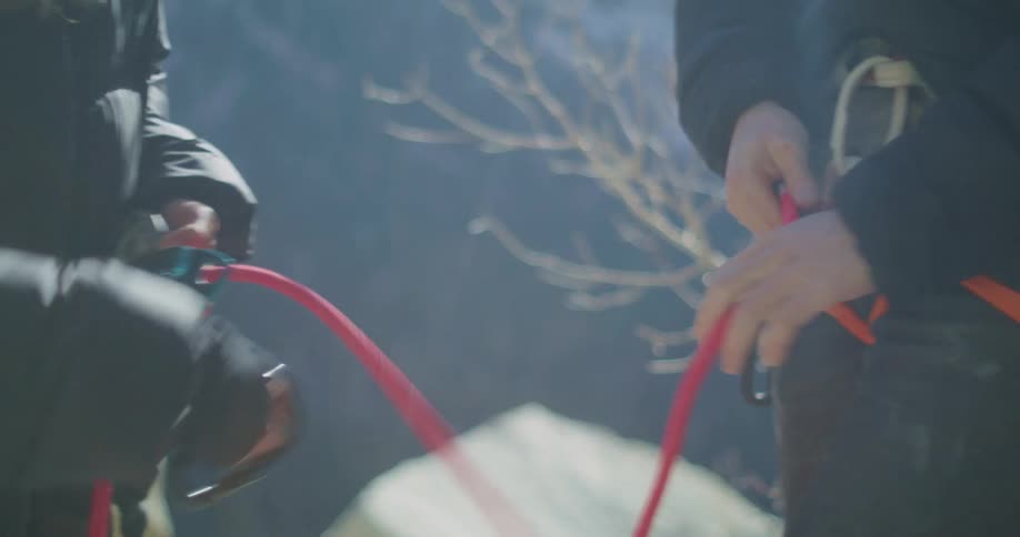 Two people prepare climbing gear handling ropes and carabiners