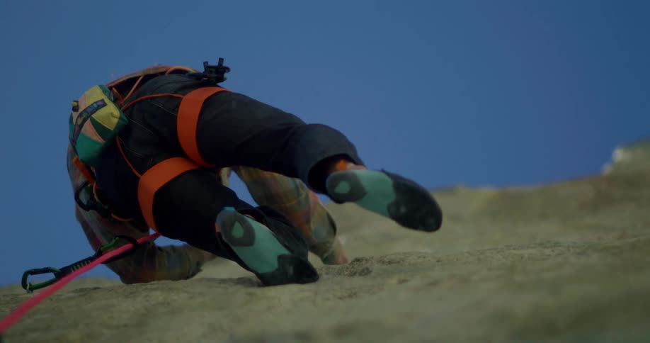 Climber equipped with rope and harness ascends rock wall