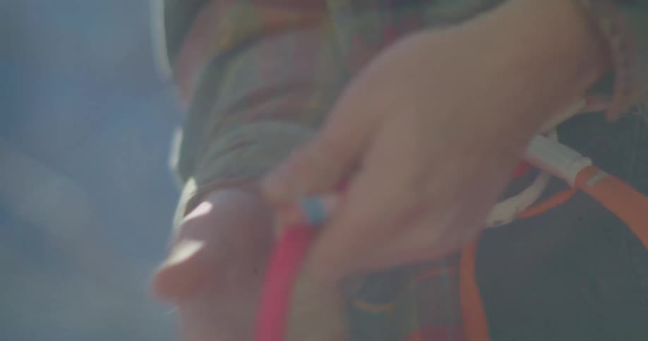 The video shows a closeup shot of a persons hands holding onto a rope or cable the person is wearing a flannel shirt