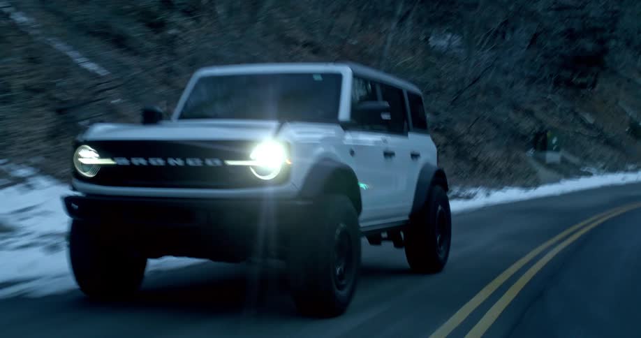 White car driving on a mountain road with snow on the sides