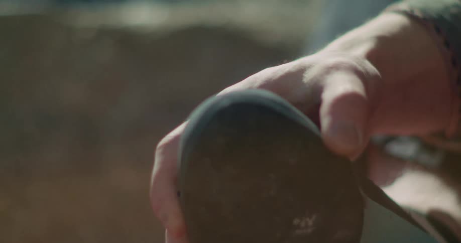 Hand adjusts climbing shoe near a red rope