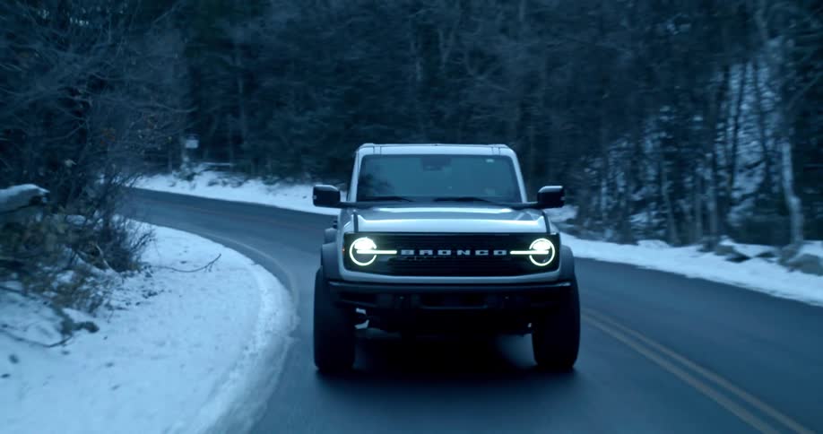 Ford bronco driving on snowy mountain road in the winter