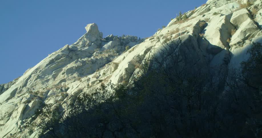 A majestic rock formation on a mountain ridge with a clear blue sky in the background