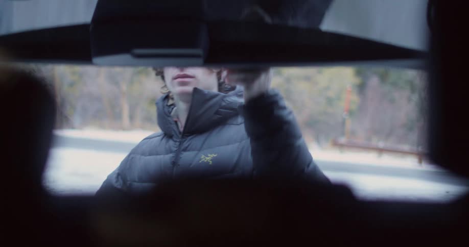 The video shows a person sitting in a car and looking to the side it appears to be nighttime as the interior of the car is dark and dimly lit