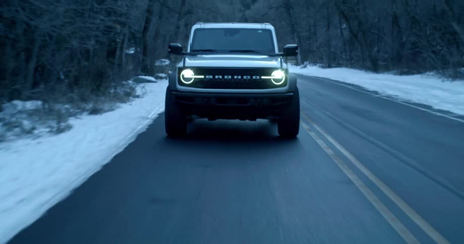 An atv driving on a road across a snowy forest park