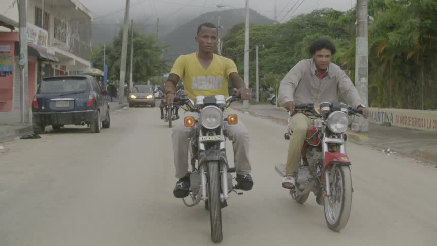 Motorcyclists ride on a town street