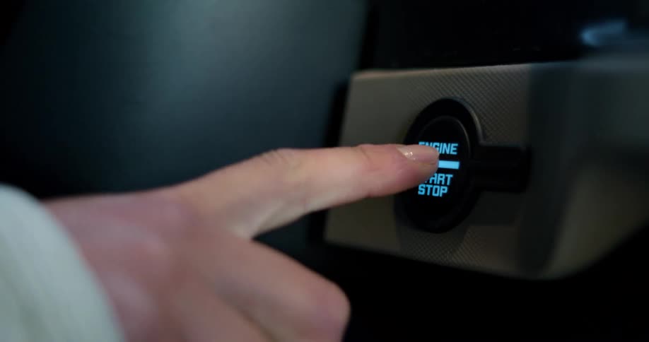 A person inside a car presses the engine start button to start the vehicle
