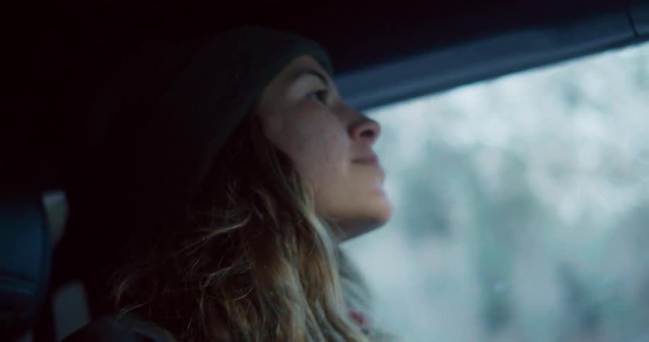 Woman wearing a beanie looks out the window while traveling by car