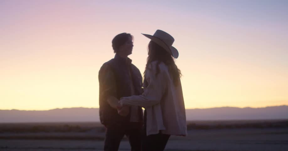 Couple dances outdoors in the rural countryside while sunlight tints the sky red