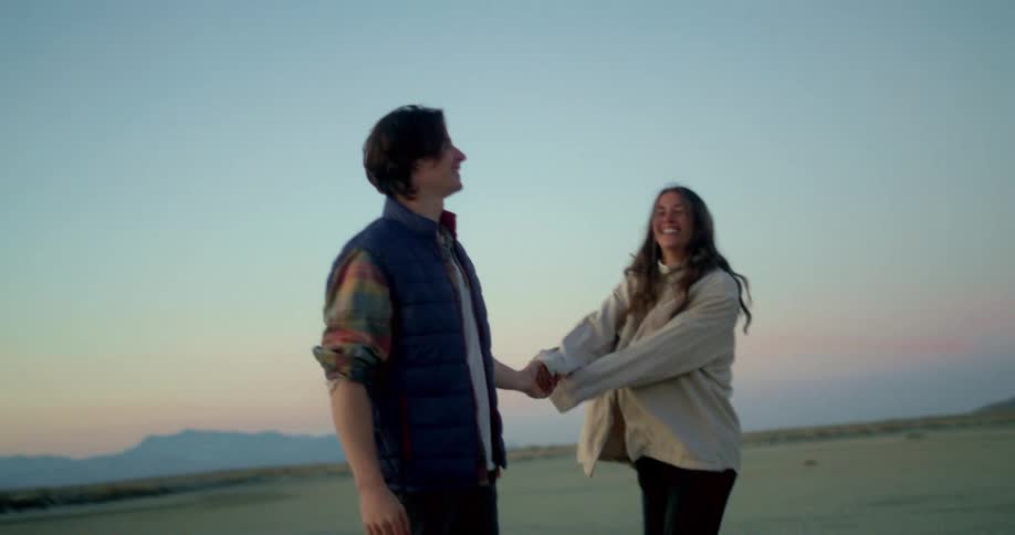 A couple has fun in an open area both wearing jackets at midday